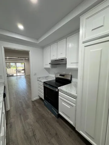 a kitchen with granite countertop a refrigerator and a stove top oven