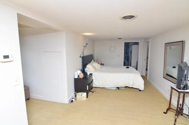 a spacious bedroom with a bed and a flat screen tv