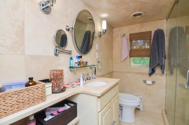 a bathroom with a granite countertop sink a toilet and mirror