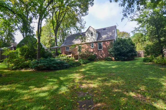 a view of a big house with a big yard and large trees