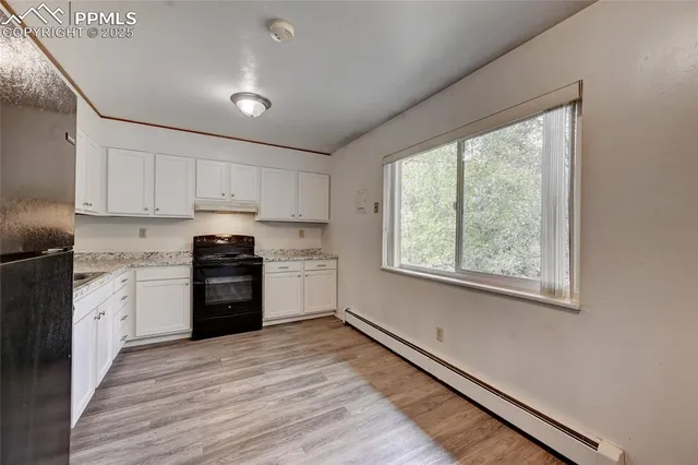 a kitchen with granite countertop a refrigerator and wooden floor