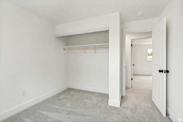 62 South Clark Lane Elk Ridge, UT 84651 - Photo 17 of 30 3rd Bedroom featuring light gray carpet, white walls, white trim, and a built-in closet with shelving and a hanging rod