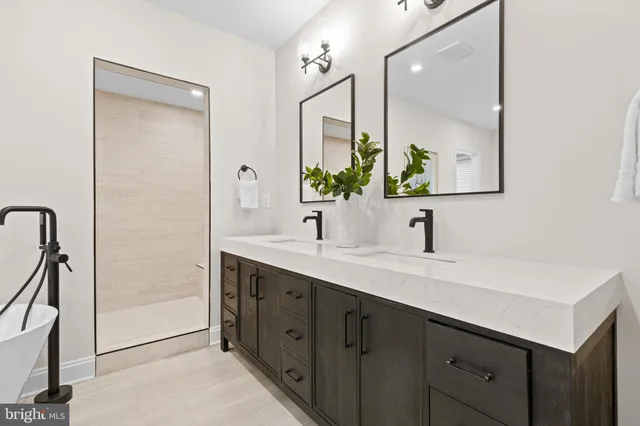 a en suite bathroom with a double vanity sink a mirror and a bathtub
