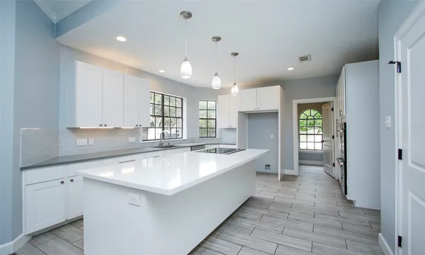 a large white kitchen with a refrigerator a sink dishwasher and a stove with wooden cabinets