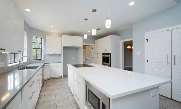 a large kitchen with kitchen island a sink a stove a refrigerator and a cabinets