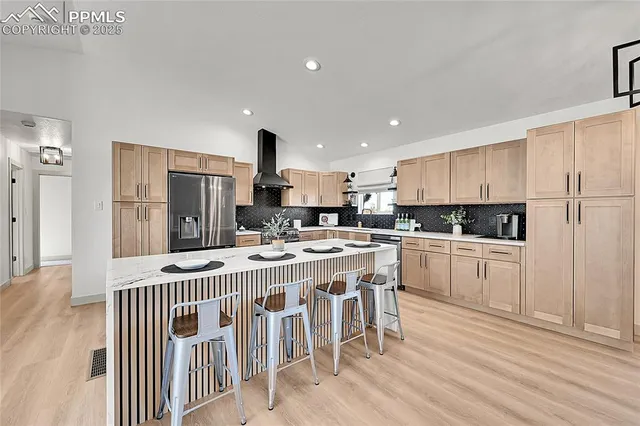 a kitchen with stainless steel appliances a refrigerator a stove a sink dishwasher and white cabinets with wooden floor