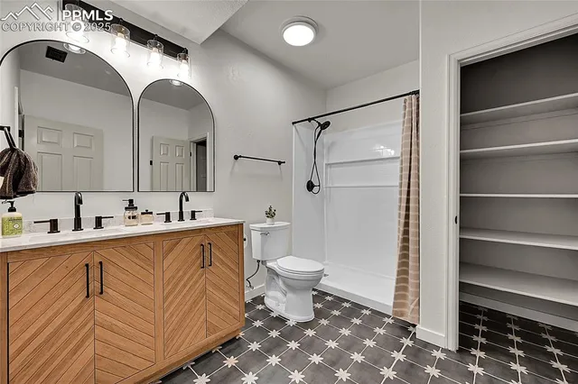 a spacious bathroom with a double vanity sink a toilet and a mirror