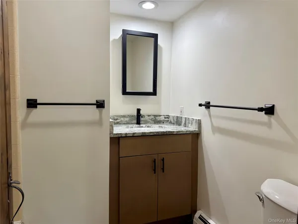 a bathroom with a granite countertop sink toilet and mirror
