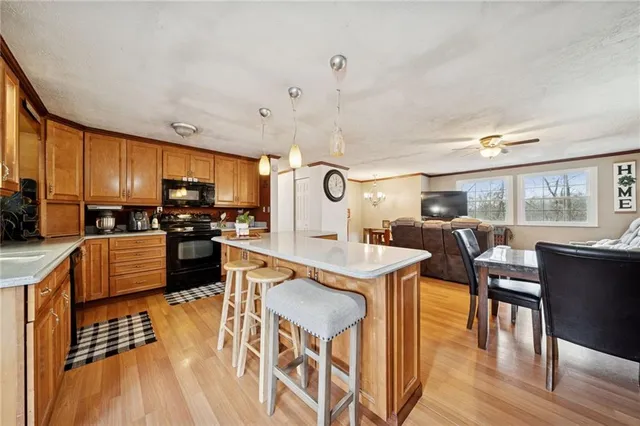 a kitchen with stainless steel appliances granite countertop a stove top oven a refrigerator a dining table and chairs with wooden floor