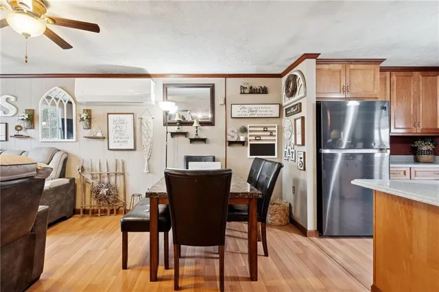 a kitchen with stainless steel appliances a refrigerator a stove a dining table and chairs with wooden floor