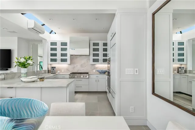 a kitchen with a sink dishwasher a stove and white cabinets with wooden floor