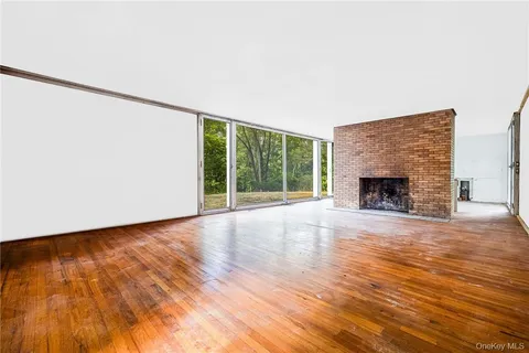 a view of an empty room with wooden floor and a fireplace