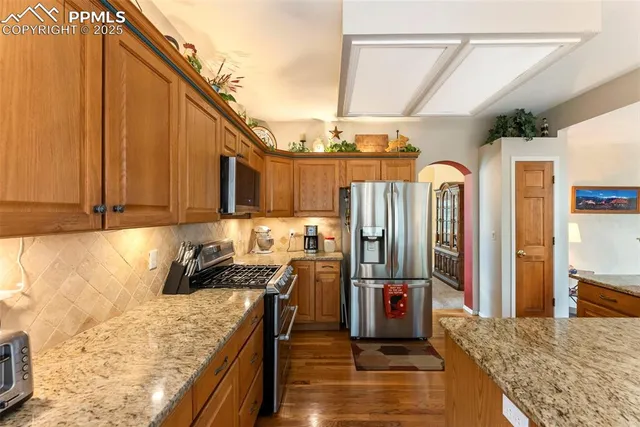 a kitchen with stainless steel appliances granite countertop a refrigerator a stove and a wooden cabinets