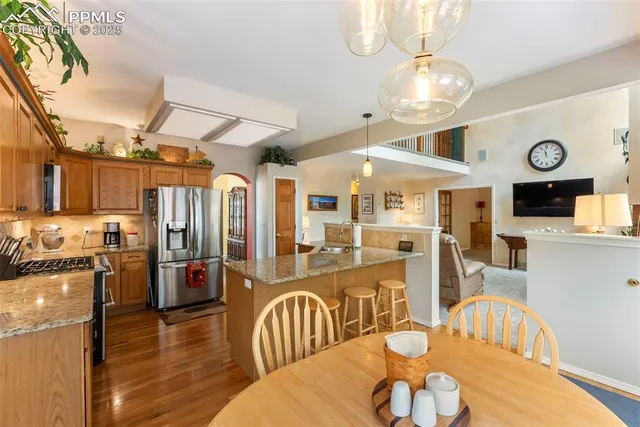 a kitchen with stainless steel appliances wooden floor dining table and chairs
