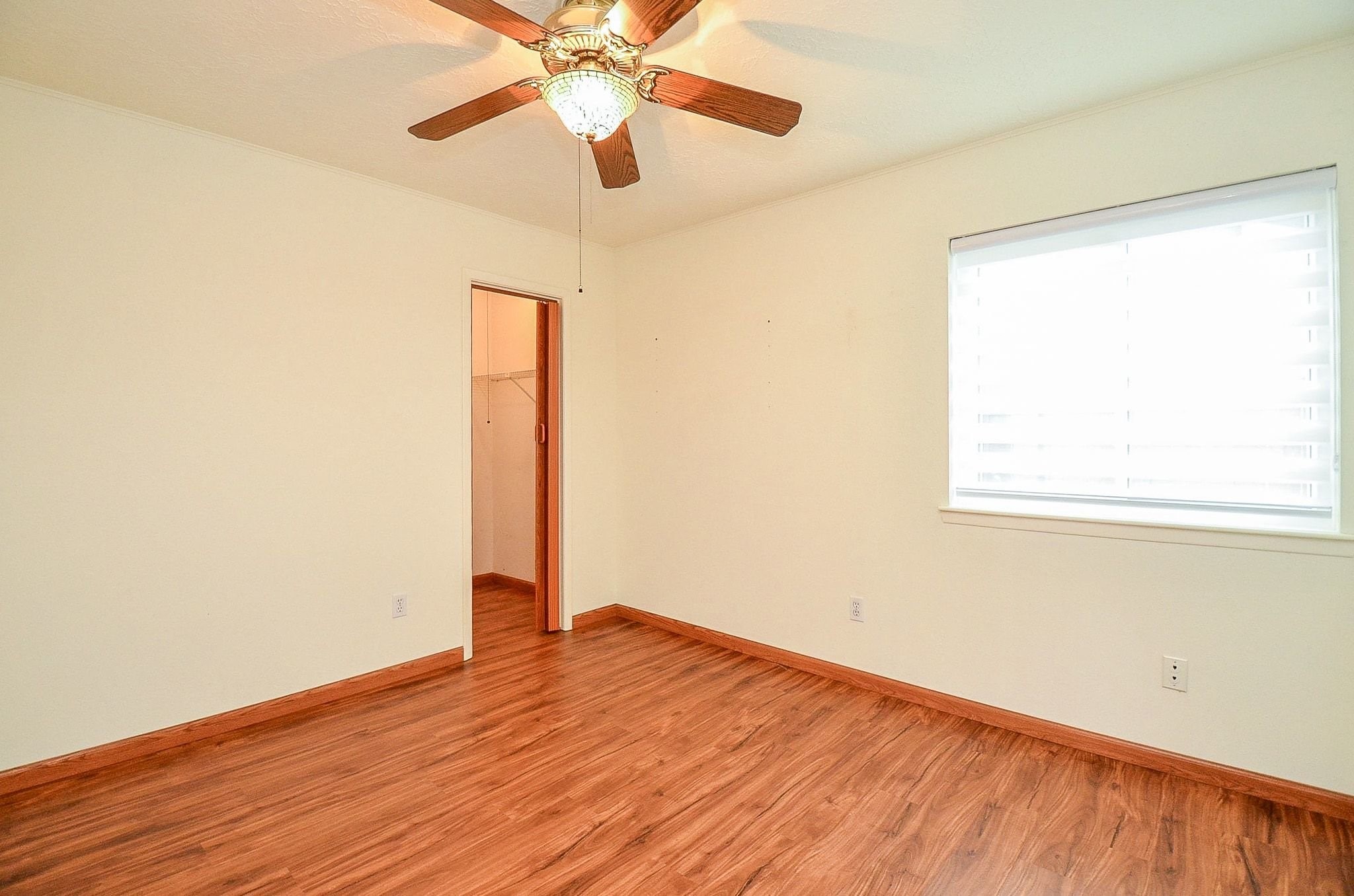 22810 John Rolfe Lane Katy, TX 77449 - Photo 17 of 20 an empty room with wooden floor chandelier fan and windows