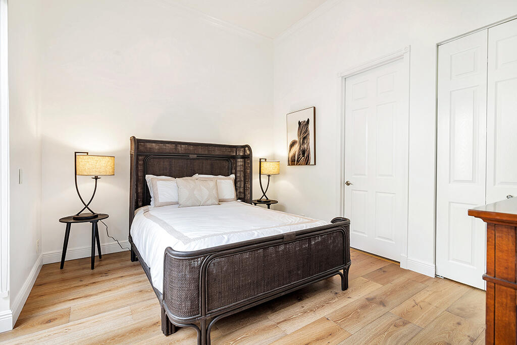 317 Galicia Way Jupiter, FL 33458 - Photo 12 of 31 a room with a bed and a potted plant on a wooden floor