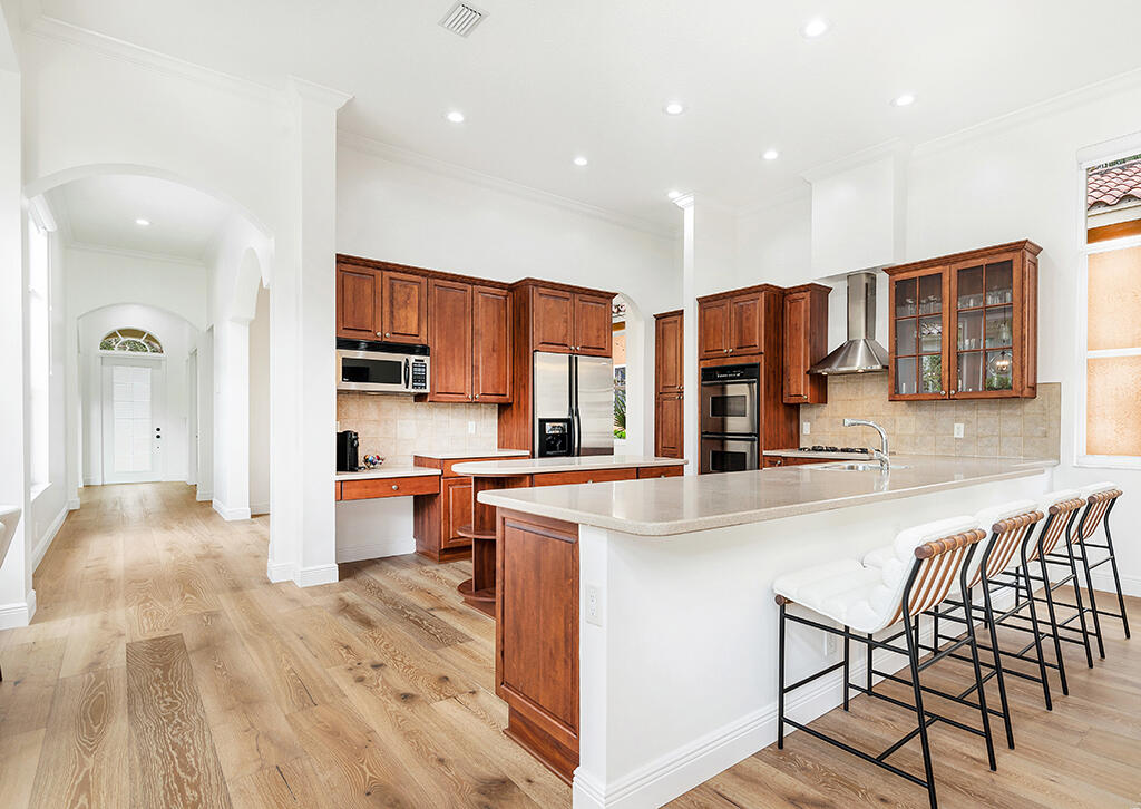 317 Galicia Way Jupiter, FL 33458 - Photo 19 of 31 a kitchen with stainless steel appliances granite countertop a stove top oven a sink dishwasher and white cabinets with wooden floor