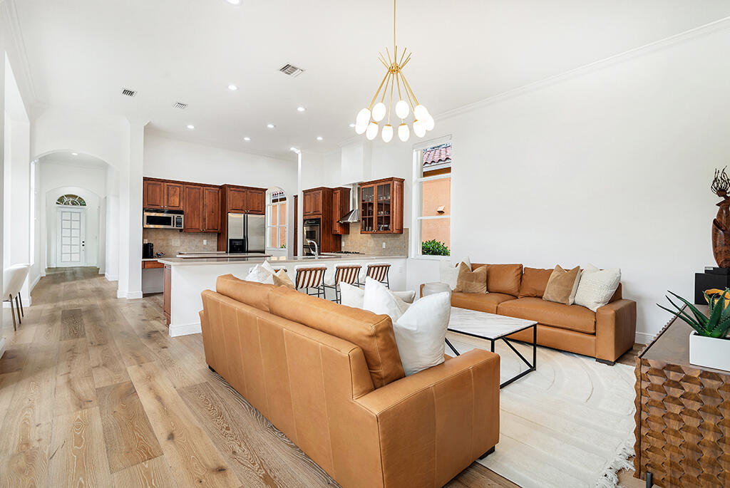 317 Galicia Way Jupiter, FL 33458 - Photo 8 of 31 a living room with furniture a chandelier and kitchen view
