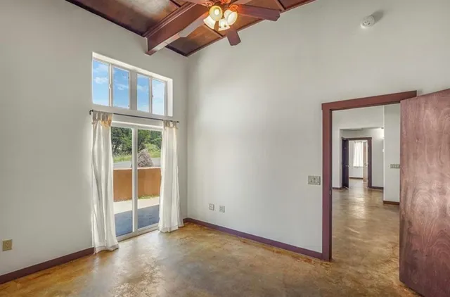 an empty room with chandelier fan and windows