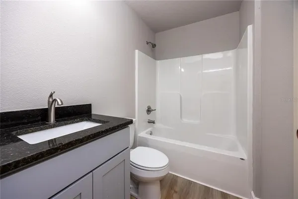 a bathroom with a granite countertop toilet sink and mirror