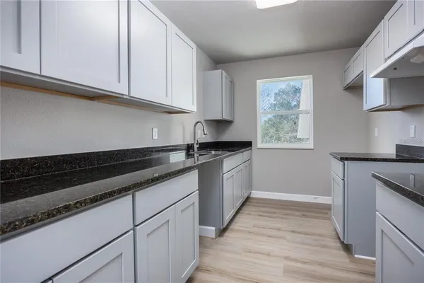 a kitchen with granite countertop wooden cabinets and a stove