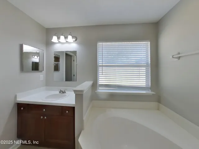 a bathroom with a sink mirror and a bathtub