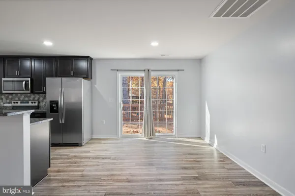 a view of kitchen with stainless steel appliances granite countertop a refrigerator a stove top oven and a wooden floors