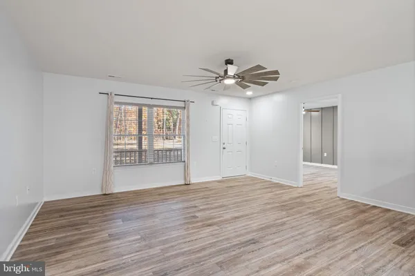 a view of an empty room with wooden floor and a window