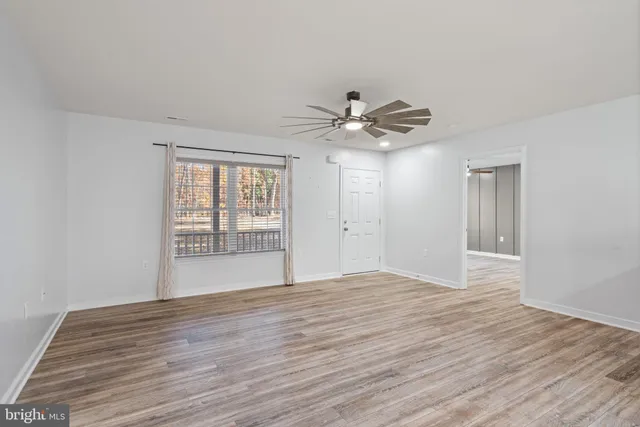 a view of an empty room with wooden floor and a window