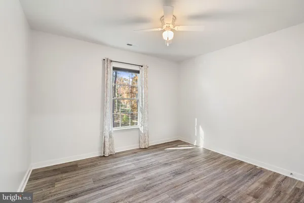 a view of a room with wooden floor and ceiling fan