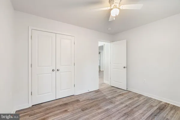 an empty room with wooden floor fan and window