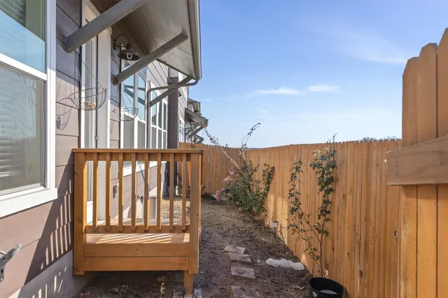 a view of a brick house with a yard and a wooden fence