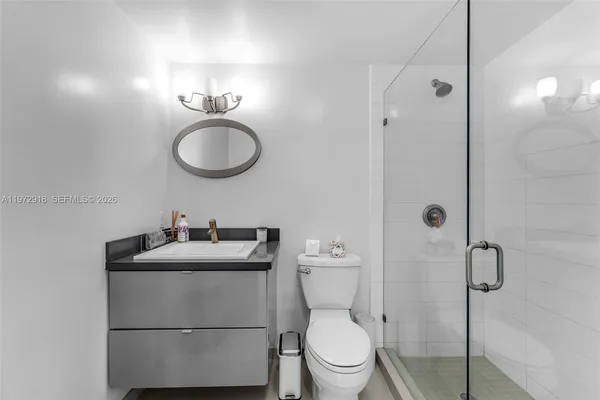 a bathroom with a toilet sink vanity granite and shower