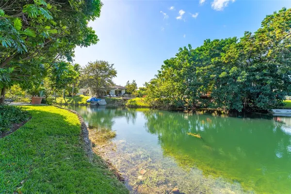 a view of a lake with a yard and large trees