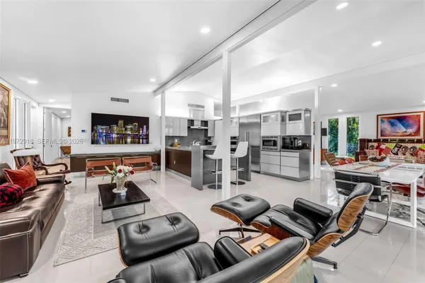 a living room with furniture kitchen view and a large window