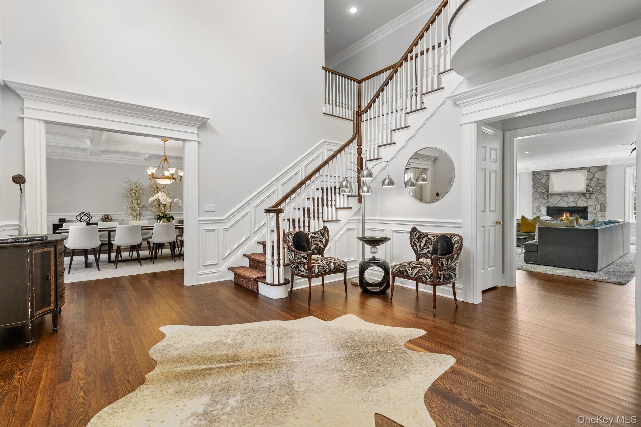 496 Long Ridge Road Bedford, NY 10576 - Photo 4 of 49 Entryway featuring stairway, dark wood-type flooring, a stone fireplace, ornamental molding, and a chandelier