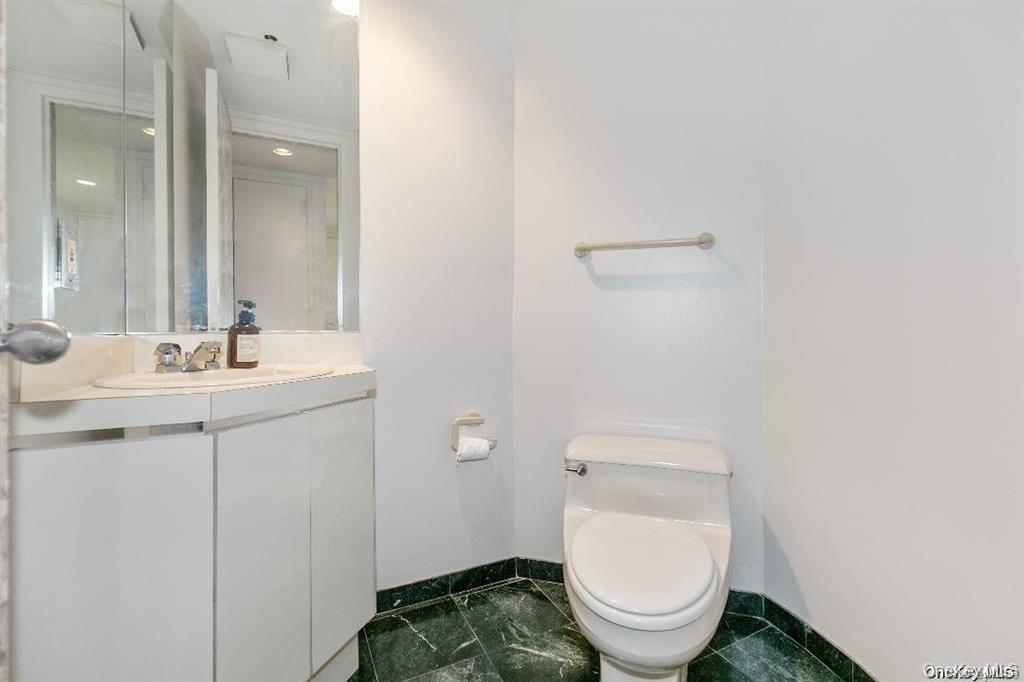 88 Cutter Mill Road, Unit 112 Great Neck, NY 11021 - Photo 6 of 12 a bathroom with a toilet a sink and mirror