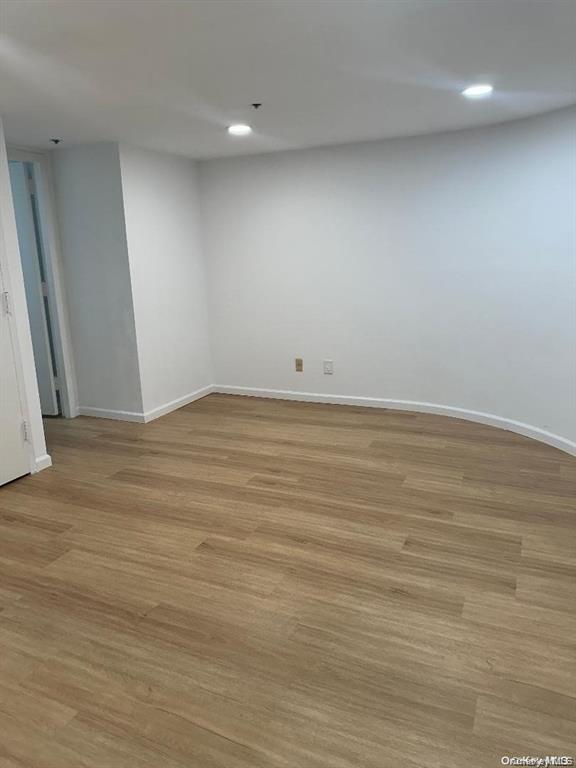88 Cutter Mill Road, Unit 112 Great Neck, NY 11021 - Photo 10 of 12 an empty room with wooden floor and windows