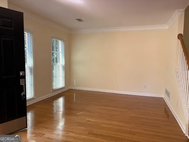 a view of an empty room with wooden floor and a window