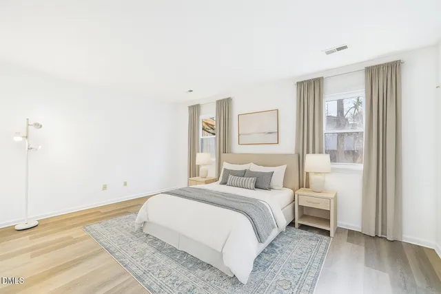 a bedroom with a white bed and wooden floor