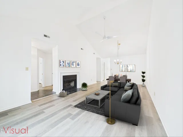 a living room with furniture a fireplace and a ceiling fan