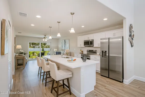 a kitchen with a dining table cabinets appliances and wooden floor