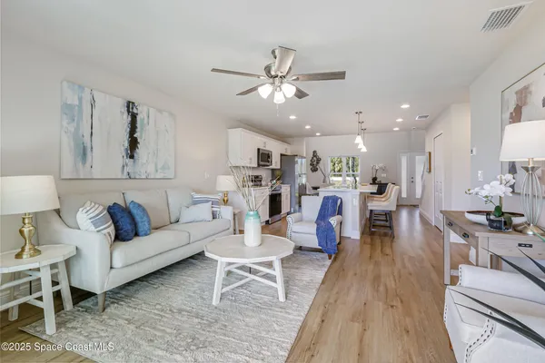 a living room with furniture kitchen view and a wooden floor