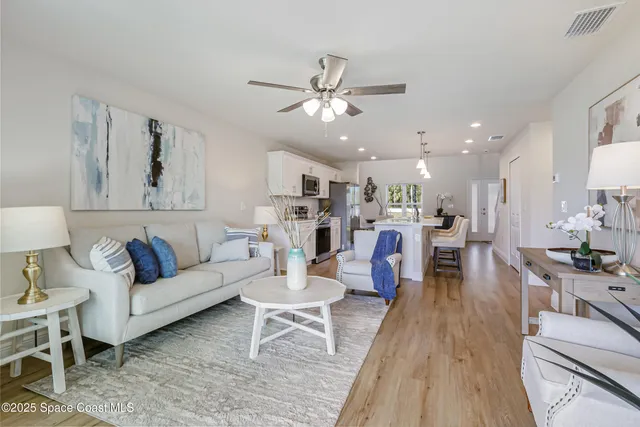 a living room with furniture kitchen view and a wooden floor