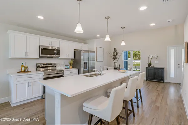 a kitchen with stainless steel appliances granite countertop a stove a sink a microwave a refrigerator a center island and furniture