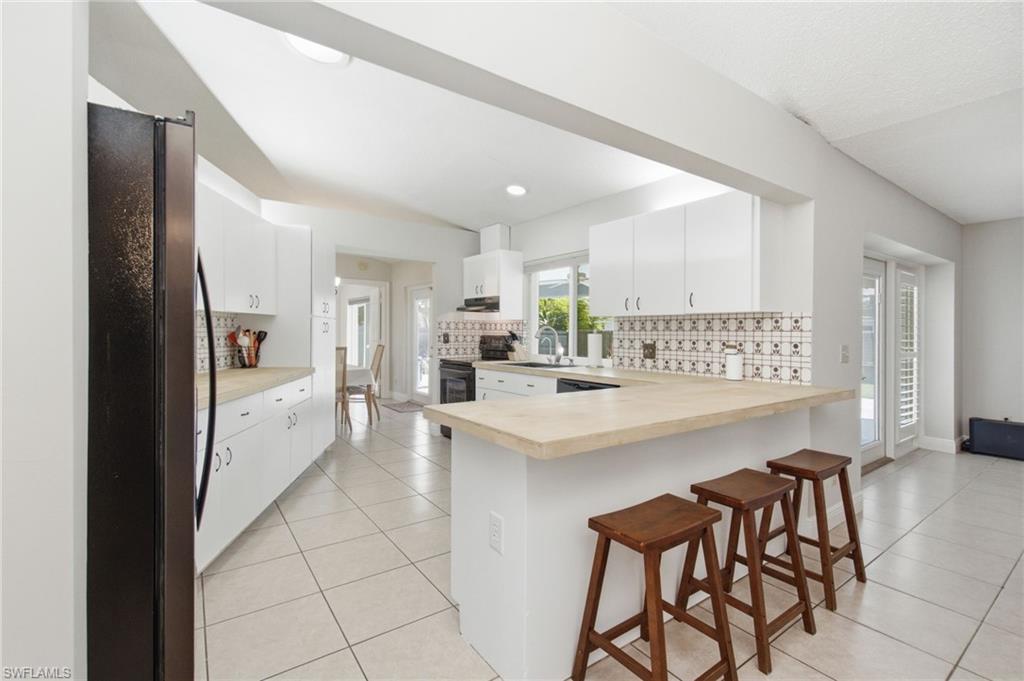 3022 47th Street Southwest Naples, FL 34116 - Photo 14 of 46 Bright kitchen featuring white cabinetry, light-toned countertops, and a patterned tile backsplash