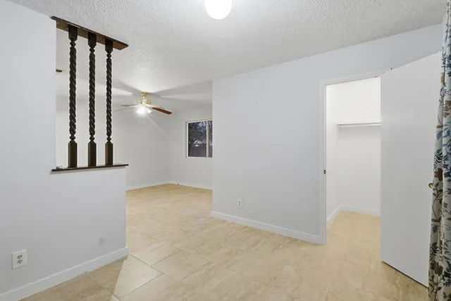 an empty room with windows and ceiling fan