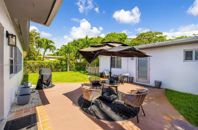 a view of a patio with couches table and chairs under an umbrella