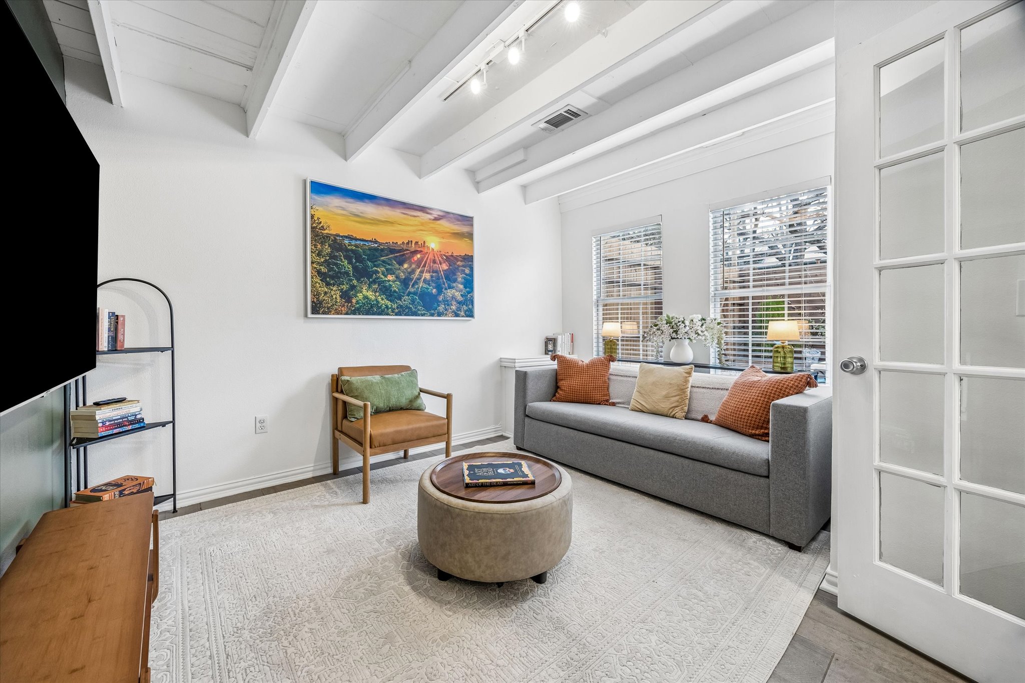 211 Lessin Lane, Unit B Austin, TX 78704 - Photo 6 of 16 This inviting living space features white walls, exposed white ceiling beams, and light wood flooring