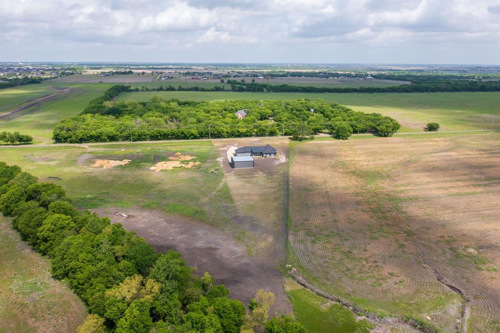 901 Old Maypearl Road Waxahachie, TX 75167 - Photo 16 of 17 The property is situated amidst expansive green fields, featuring a well-maintained building with a dark roof